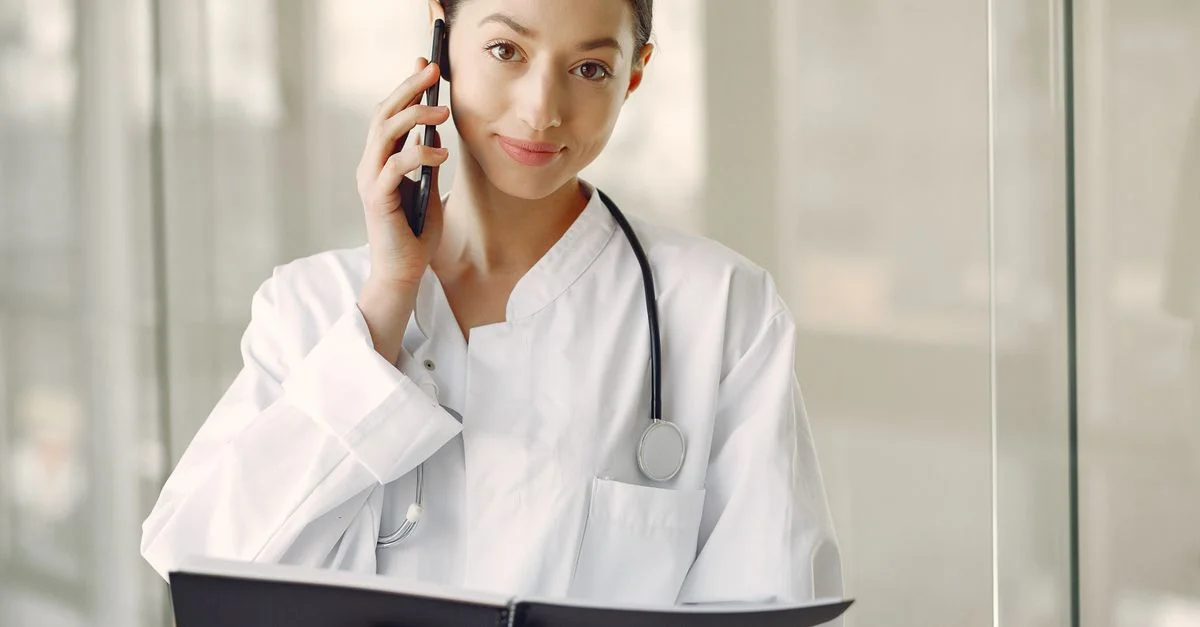Médecin femme professionnelle en blouse blanche parlant au téléphone dans une clinique médicale.