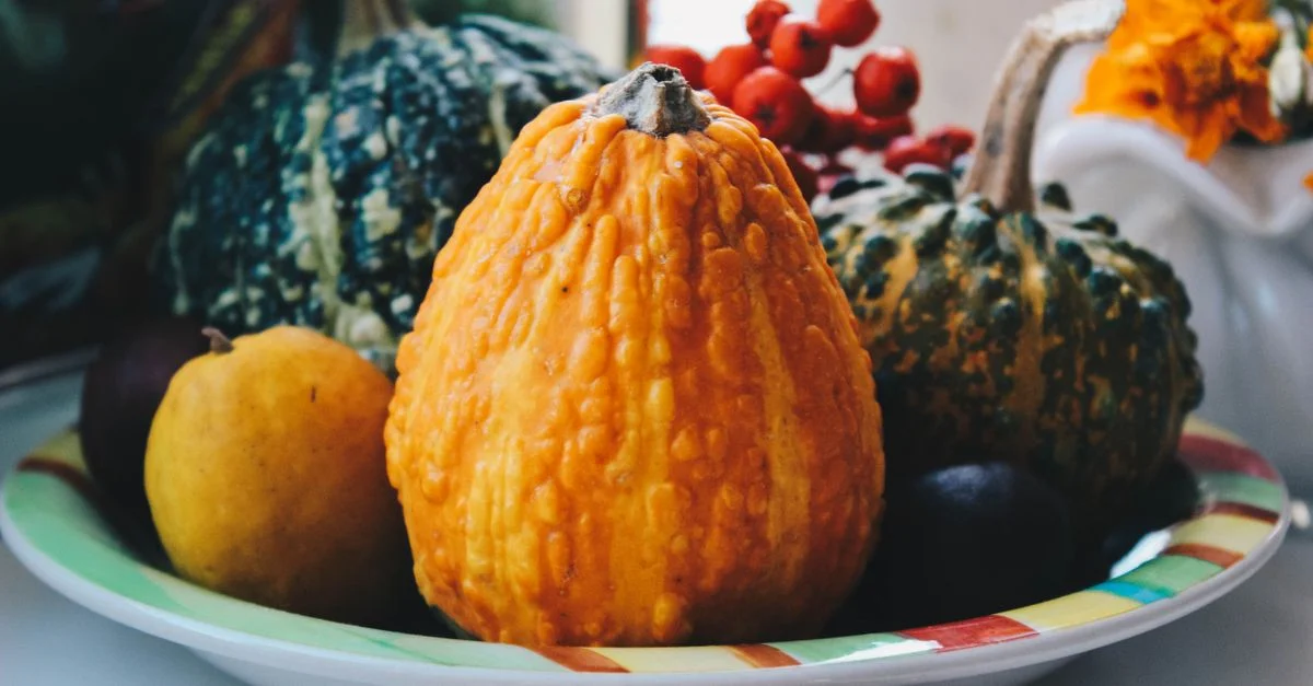 Un assortiment coloré de courges et de fruits d'automne dans un bol décoratif, mettant en valeur la récolte d'automne.
