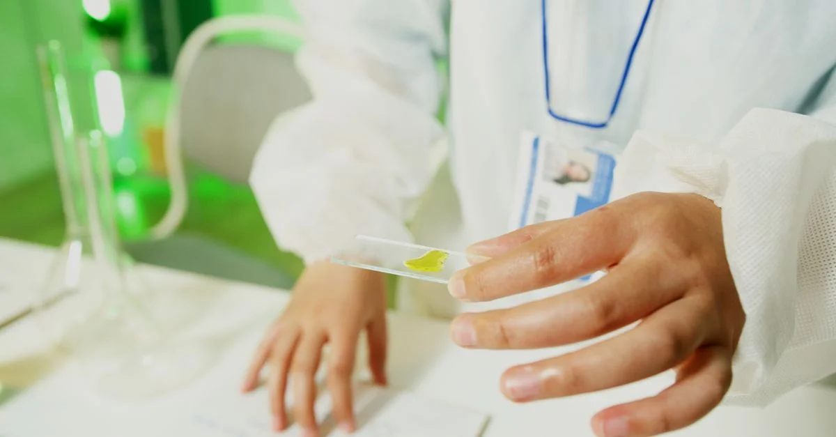 Chercheur en blouse de laboratoire tenant une lame en verre, réalisant une expérience.
